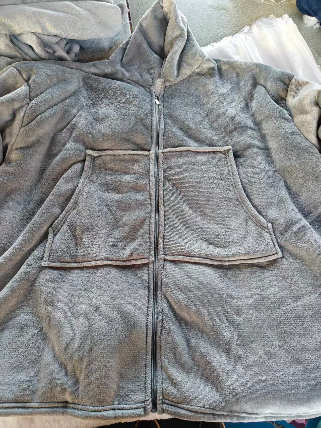 Gray fleece jacket with a hood on a flat surface