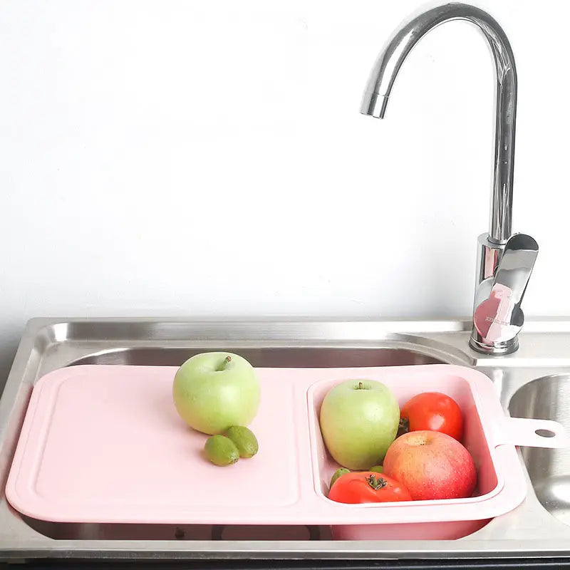 Pink Multifunctional Sink Chopping Board with Drain Basket and fresh fruits in the basket in a kitchen sink