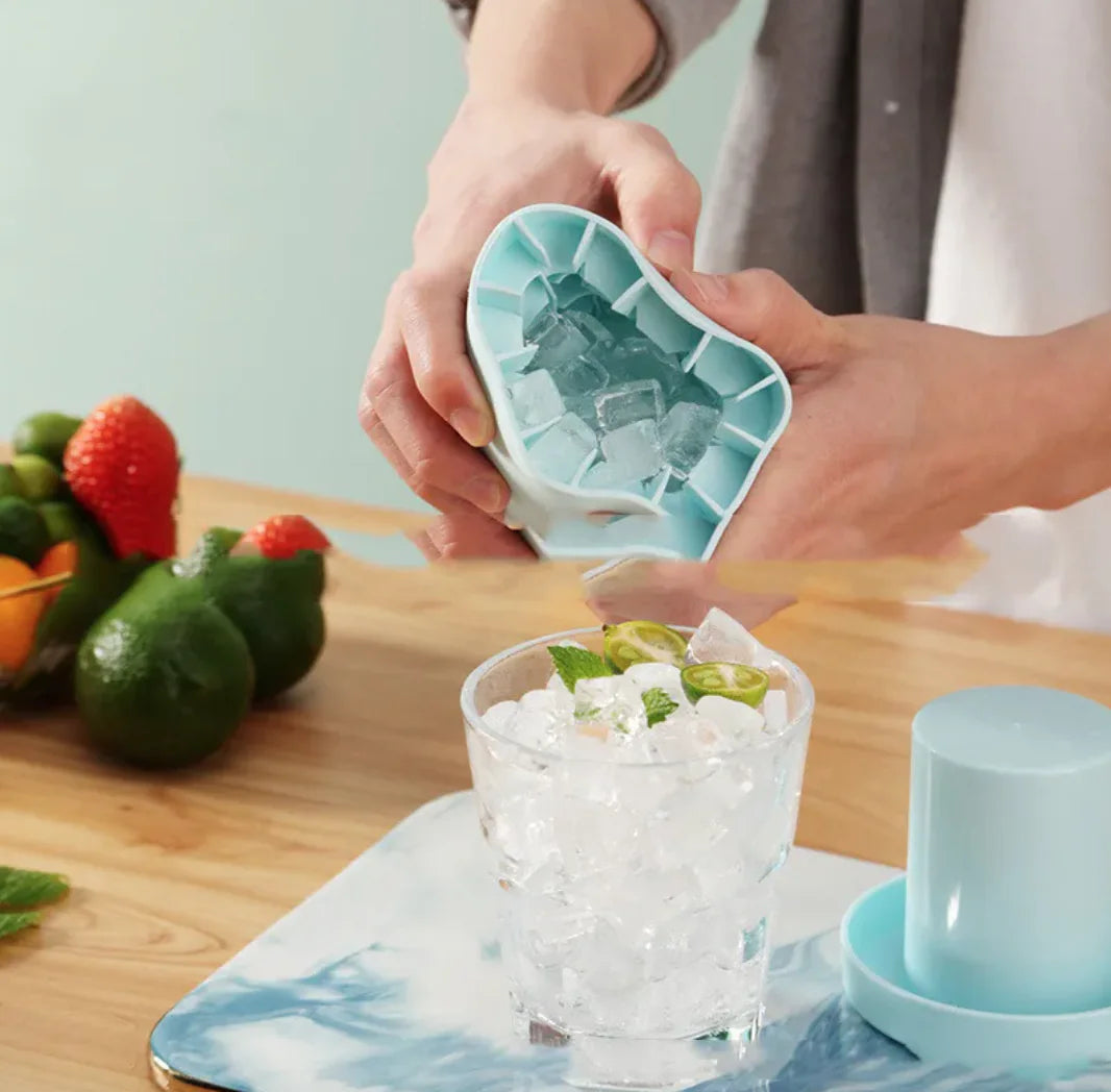 Person using Portable 2-in-1 Ice Bucket and Cube Maker to make ice cubes on a table with a glass of a dessert.