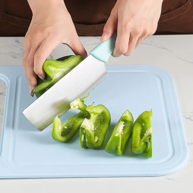 Person slicing green bell peppers on a blue Multifunctional Sink Chopping Board with the Drain Basket out using a knife. 